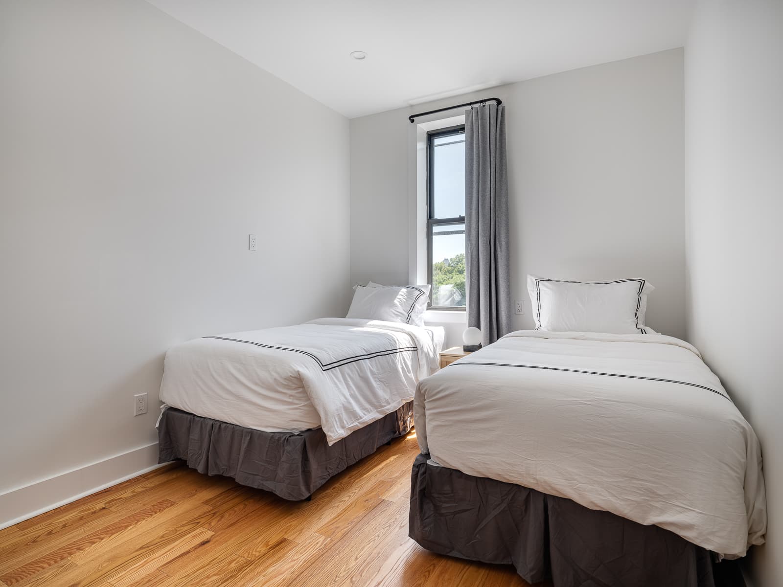 Twin bedroom with two beds in white linens and a window onto trees